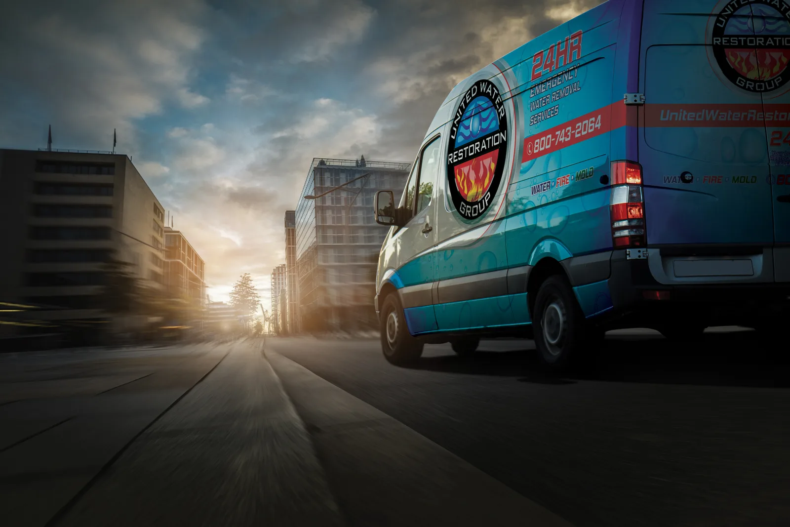 A United Water Restoration Group van driving through a city street at sunrise